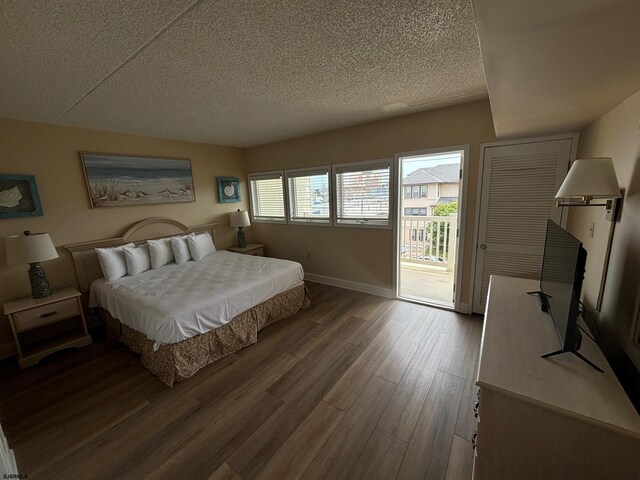 bedroom with access to exterior, hardwood / wood-style floors, and a textured ceiling