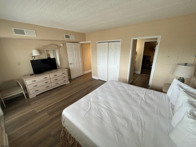 bedroom with dark hardwood / wood-style floors, a textured ceiling, and a closet