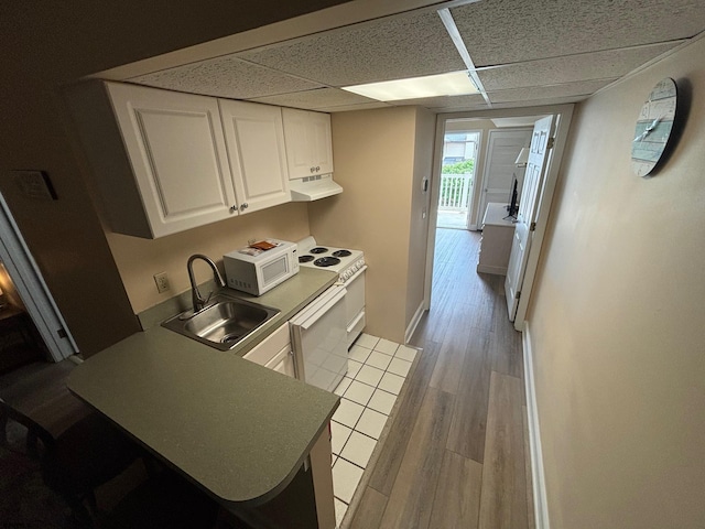 kitchen with sink, a drop ceiling, light hardwood / wood-style floors, white appliances, and white cabinets