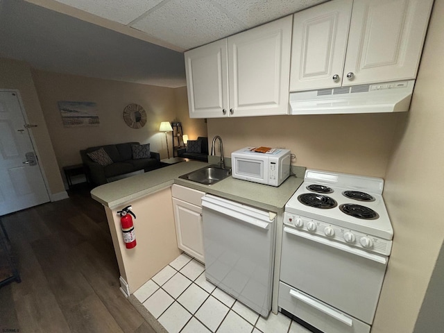 kitchen with white appliances, white cabinets, sink, light hardwood / wood-style flooring, and kitchen peninsula