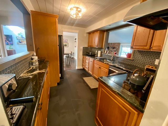 kitchen with backsplash, sink, appliances with stainless steel finishes, dark tile patterned floors, and range hood