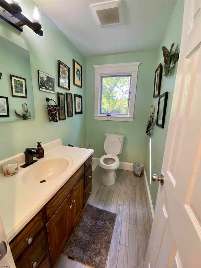 bathroom with wood-type flooring, toilet, and vanity