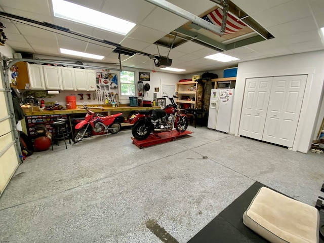 garage featuring white fridge with ice dispenser, a workshop area, and a garage door opener