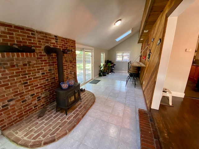 corridor featuring brick wall, light hardwood / wood-style floors, and lofted ceiling with skylight