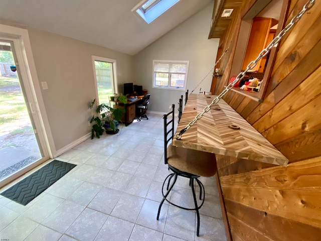 interior space featuring vaulted ceiling with skylight and light tile patterned floors