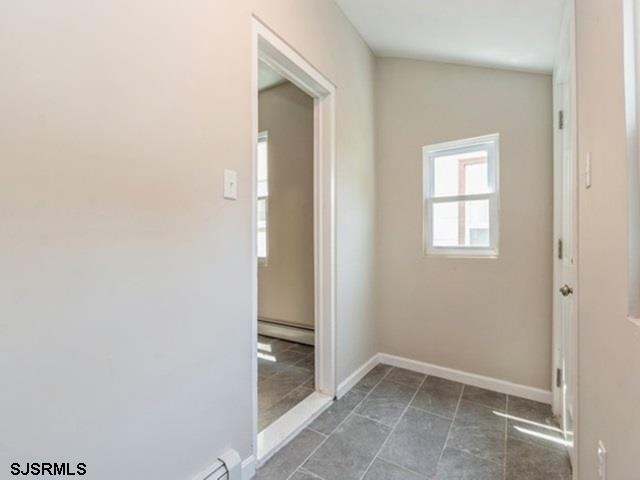 interior space with vaulted ceiling, baseboard heating, and tile patterned floors