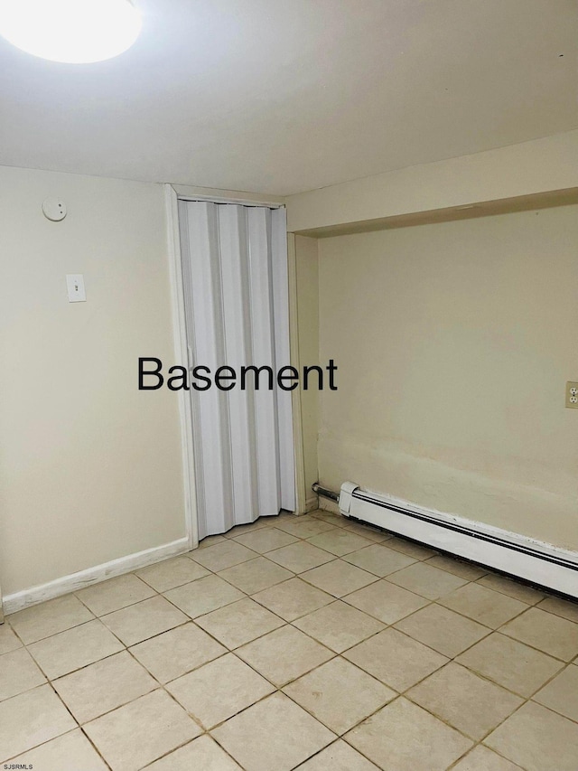 empty room featuring a baseboard heating unit and light tile patterned flooring