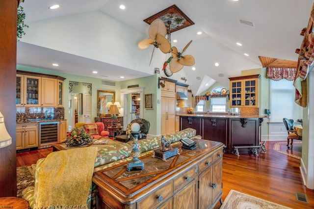 living room with beverage cooler, ceiling fan, high vaulted ceiling, and dark hardwood / wood-style flooring