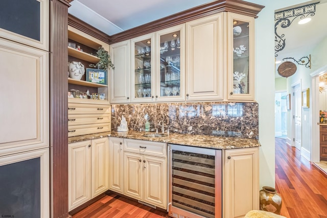 bar featuring dark hardwood / wood-style flooring, sink, dark stone counters, beverage cooler, and tasteful backsplash