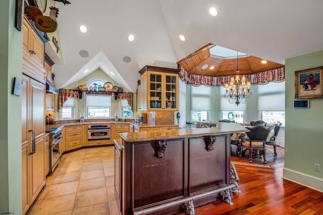 kitchen with a breakfast bar area, stainless steel appliances, a skylight, light wood-type flooring, and dark stone counters