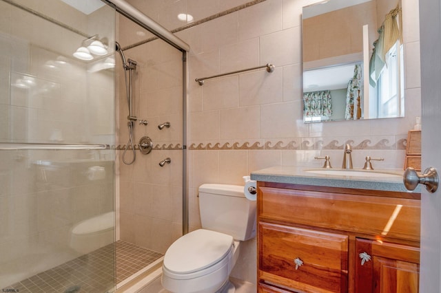 bathroom with vanity, tile walls, toilet, and a shower with door