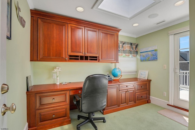 carpeted office space featuring crown molding, built in desk, and plenty of natural light