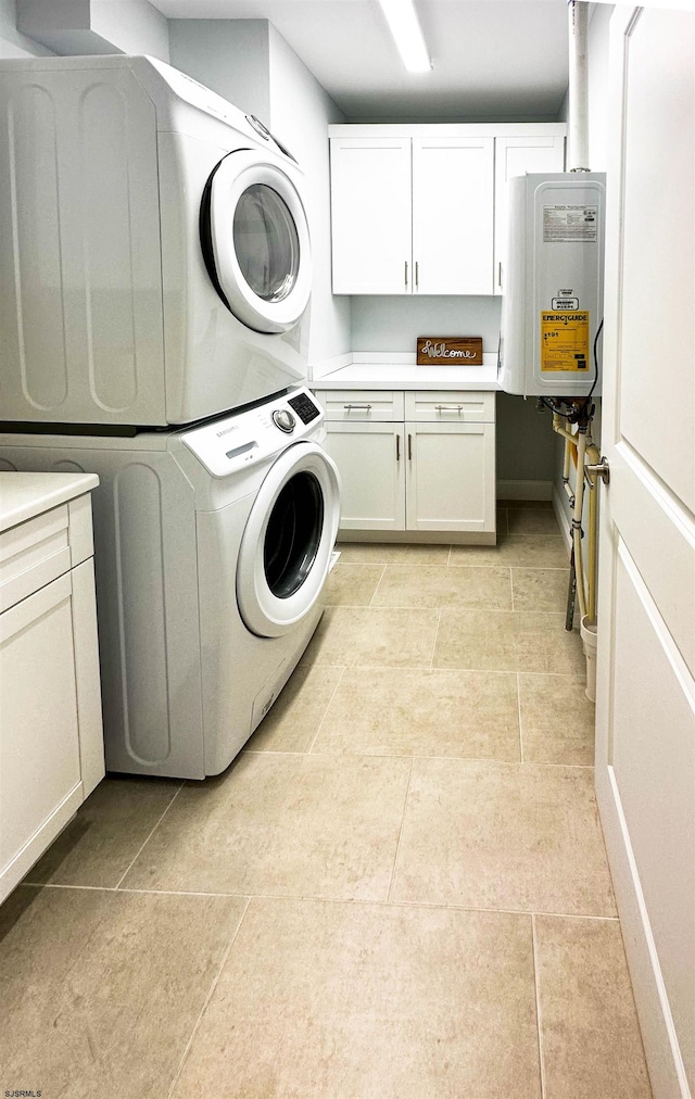 clothes washing area featuring light tile patterned floors, stacked washing maching and dryer, cabinets, and water heater