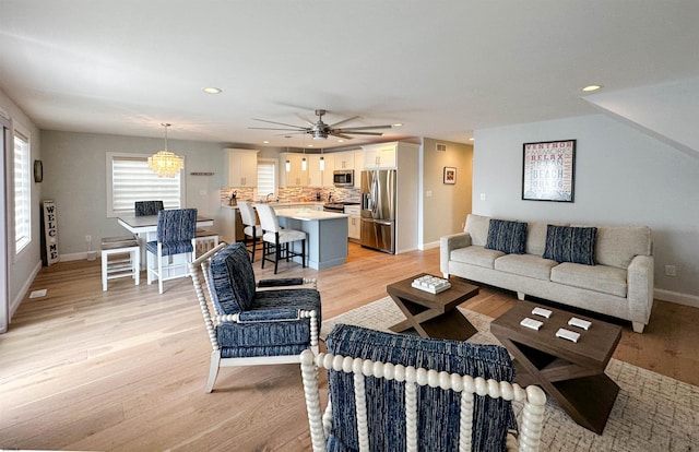 living room featuring light wood-type flooring, sink, and ceiling fan