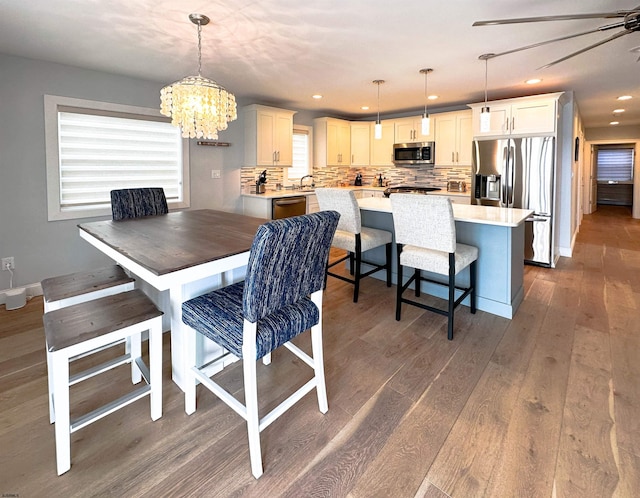 dining room featuring ceiling fan with notable chandelier and dark hardwood / wood-style flooring