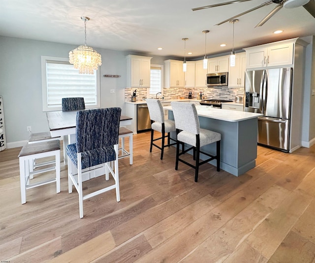 interior space with light hardwood / wood-style flooring, sink, and ceiling fan with notable chandelier