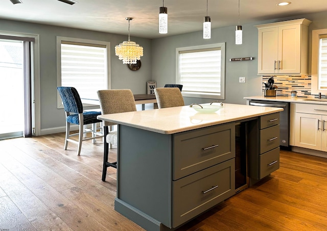 kitchen featuring gray cabinetry, backsplash, light stone counters, plenty of natural light, and wood-type flooring