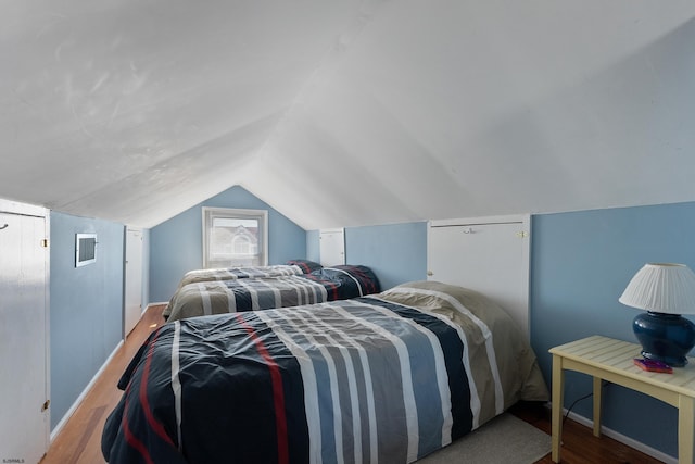 bedroom featuring lofted ceiling, wood finished floors, visible vents, and baseboards