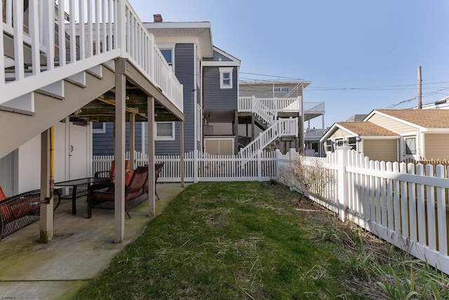 back of property featuring a patio area, a fenced backyard, a yard, and stairway