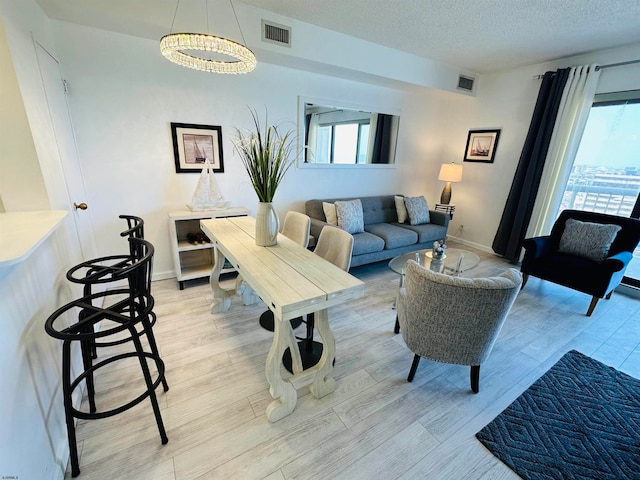 living room with an inviting chandelier, light hardwood / wood-style floors, and a textured ceiling