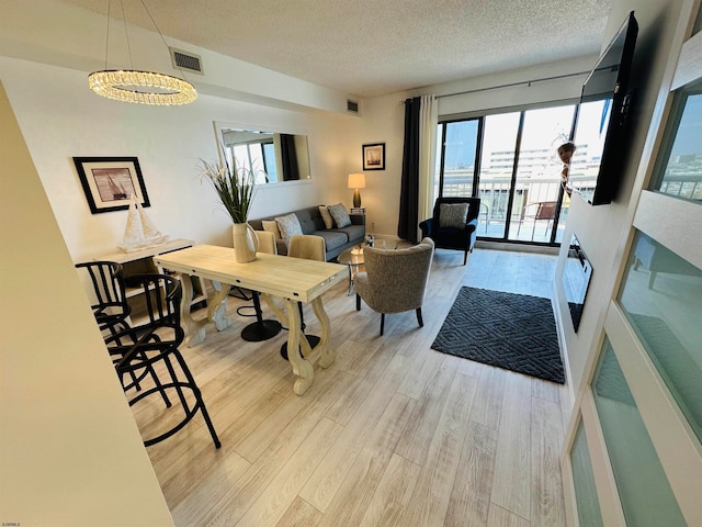 living room featuring a textured ceiling, a notable chandelier, and light hardwood / wood-style floors