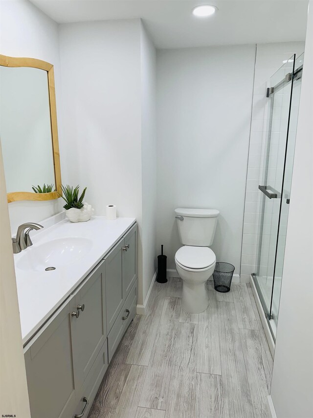 bathroom with vanity, toilet, hardwood / wood-style flooring, and a shower with shower door