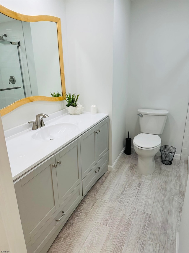 bathroom with vanity, toilet, hardwood / wood-style flooring, and walk in shower