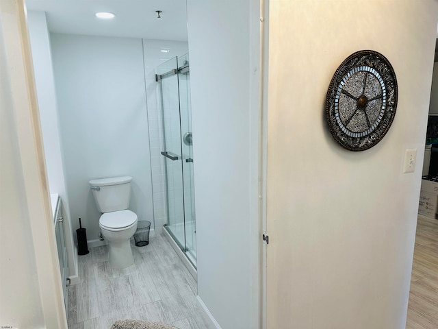 bathroom featuring toilet, hardwood / wood-style flooring, and a shower with door