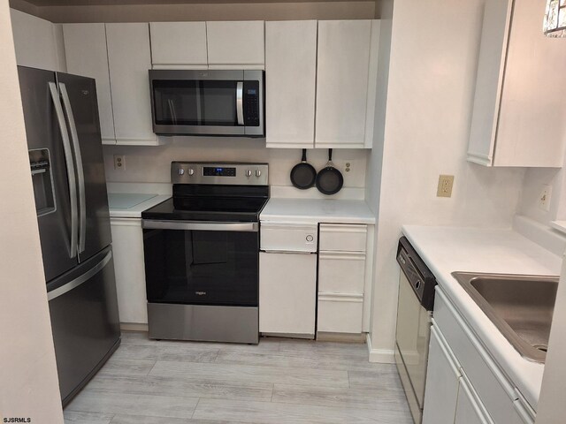 kitchen with stainless steel appliances, light wood-type flooring, and white cabinets