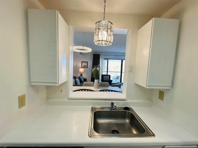 kitchen with an inviting chandelier, sink, white cabinets, and hanging light fixtures