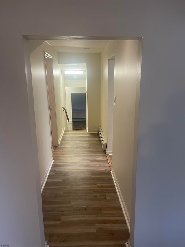 hallway featuring a baseboard heating unit and dark hardwood / wood-style flooring