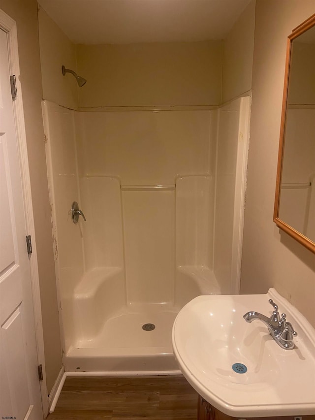 bathroom with a shower, sink, and hardwood / wood-style floors