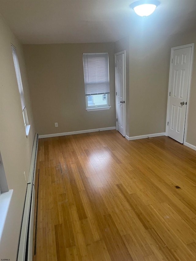 empty room with light hardwood / wood-style flooring and a baseboard radiator