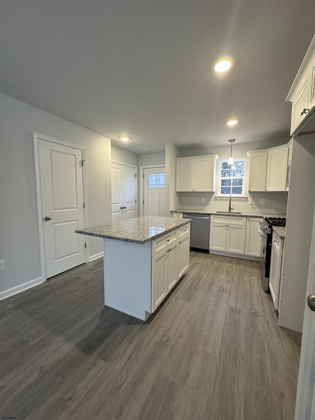 kitchen with a center island, dark wood-type flooring, white cabinets, hanging light fixtures, and appliances with stainless steel finishes