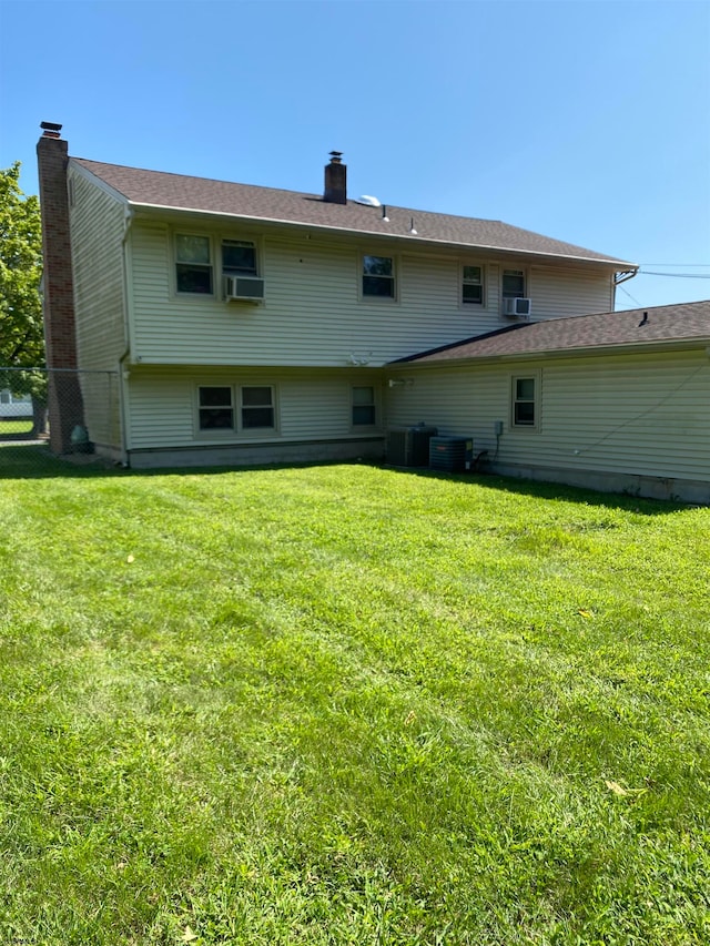 rear view of property with central AC and a yard