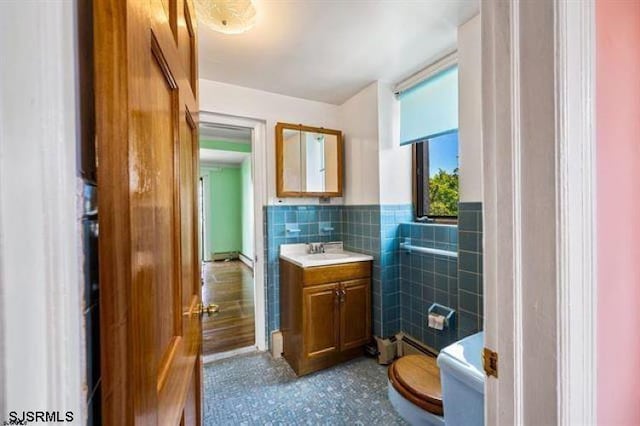 bathroom featuring vanity, toilet, and tile walls