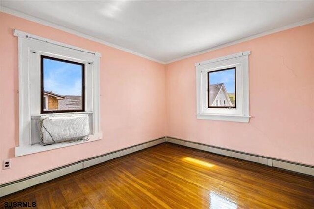 empty room with crown molding, a baseboard radiator, and hardwood / wood-style flooring