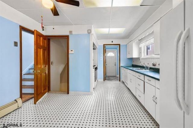 kitchen featuring white fridge, baseboard heating, sink, ceiling fan, and white cabinets