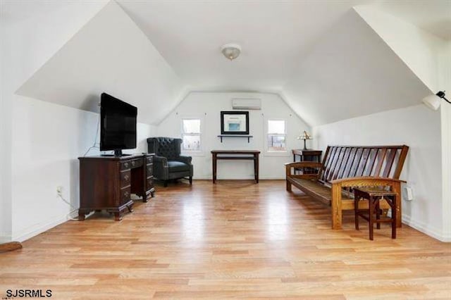 interior space with light wood-type flooring, lofted ceiling, and a wall mounted AC