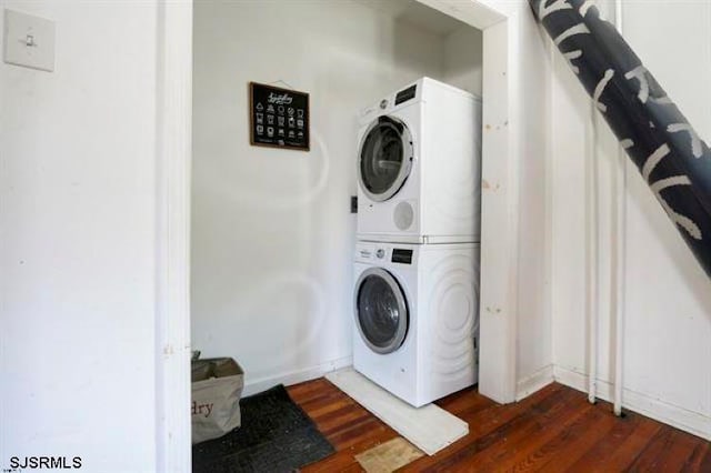 laundry room featuring stacked washer and clothes dryer and dark hardwood / wood-style floors