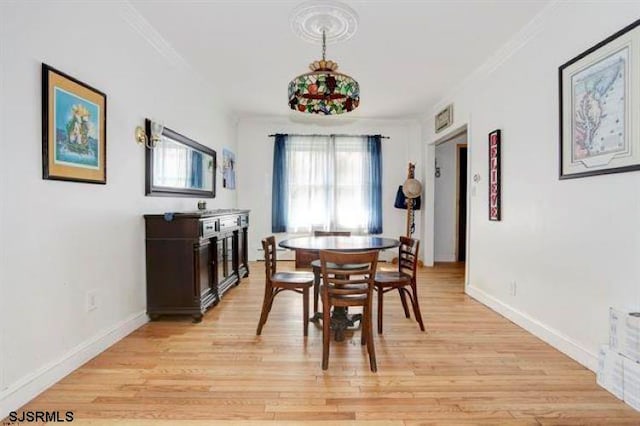 dining space with ornamental molding and light hardwood / wood-style floors