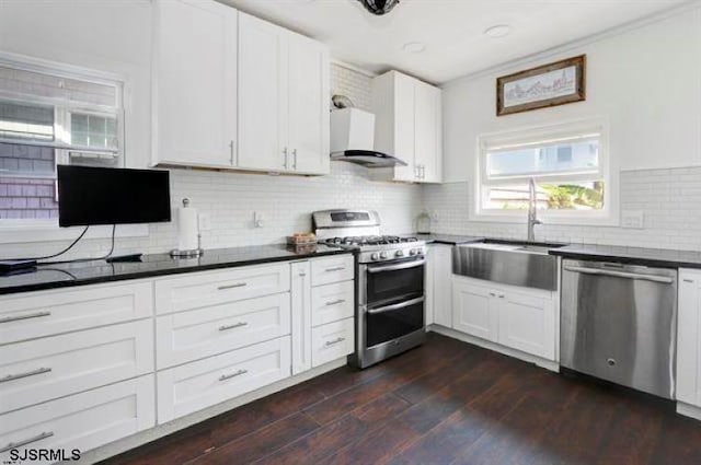 kitchen featuring wall chimney exhaust hood, dark hardwood / wood-style flooring, backsplash, appliances with stainless steel finishes, and white cabinets