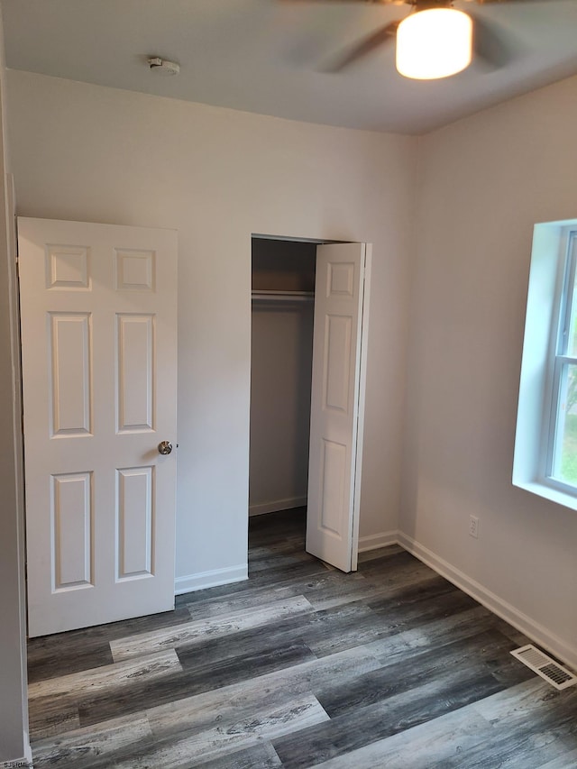 unfurnished bedroom featuring ceiling fan, a closet, and dark hardwood / wood-style flooring