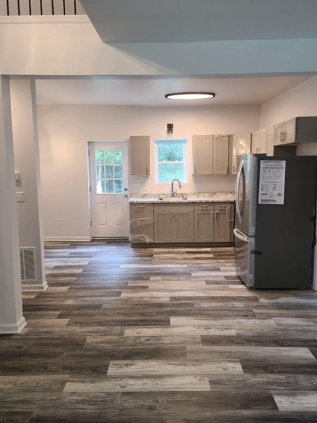 kitchen with dark wood-type flooring, stainless steel refrigerator, sink, and gray cabinets