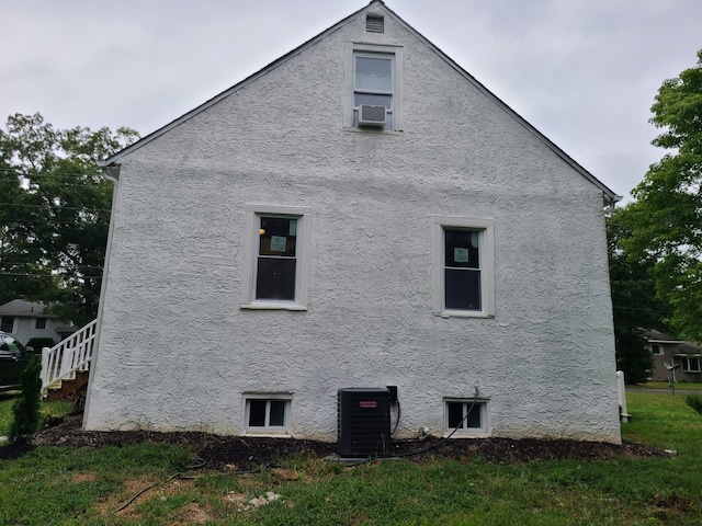 view of side of property with cooling unit and a lawn