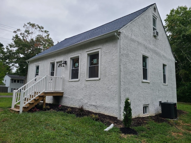 view of front of house with a front yard and central air condition unit