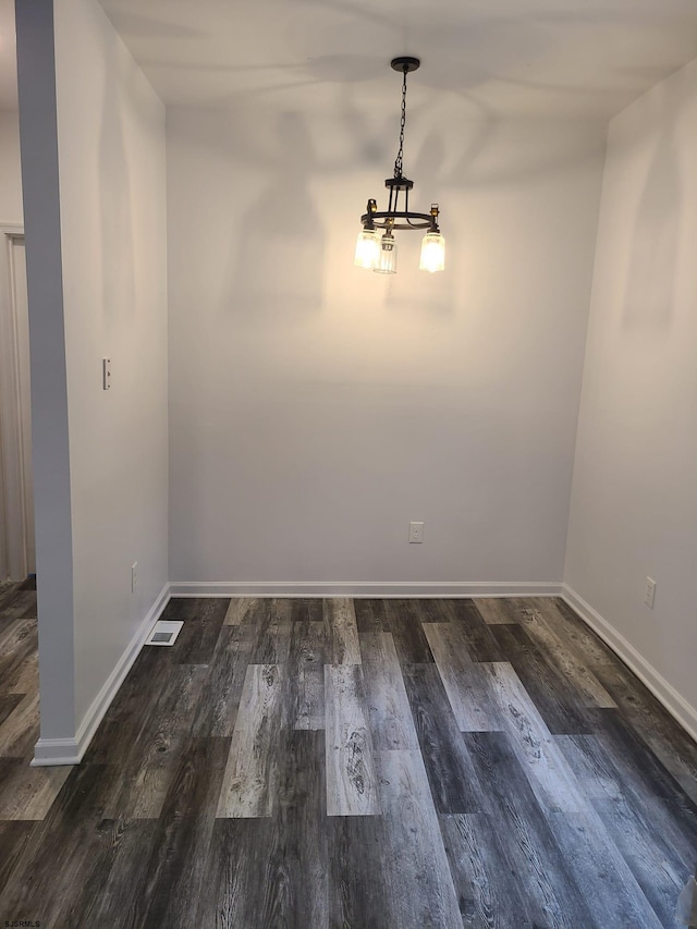 spare room with dark wood-type flooring and a chandelier