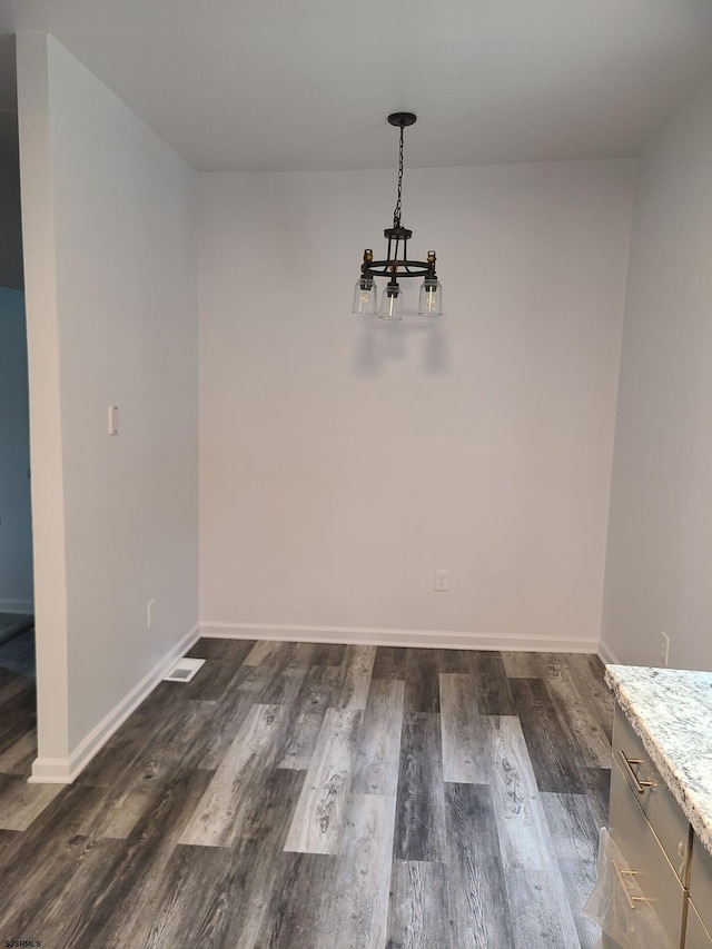 unfurnished dining area with dark hardwood / wood-style flooring and an inviting chandelier