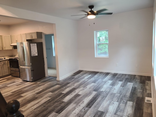 kitchen with dark wood-type flooring, ceiling fan, stove, and stainless steel refrigerator