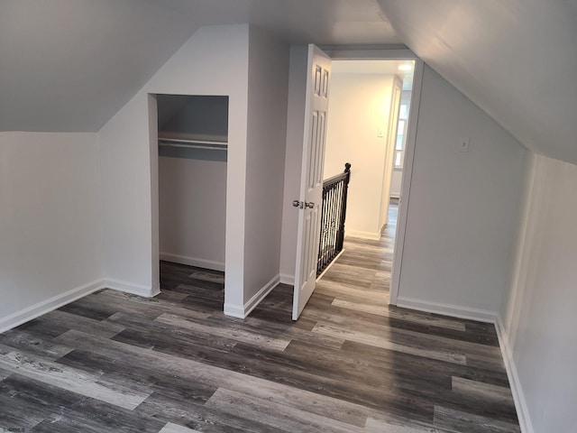 additional living space featuring dark wood-type flooring and vaulted ceiling